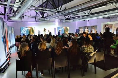 Intérieur d'un grand espace industriel lumineux avec sol clair, murs blancs, poutres métalliques et conduits apparents.
