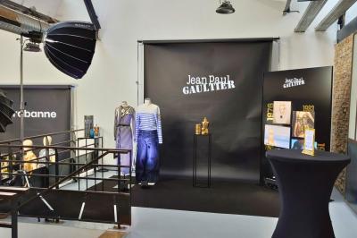 Intérieur d'un grand espace industriel lumineux avec sol clair, murs blancs, poutres métalliques et conduits apparents.