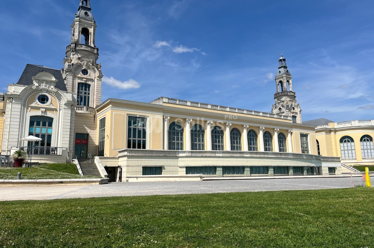 Bâtiment historique avec deux tours et une façade jaune, entouré d'une pelouse et d'un ciel dégagé.
