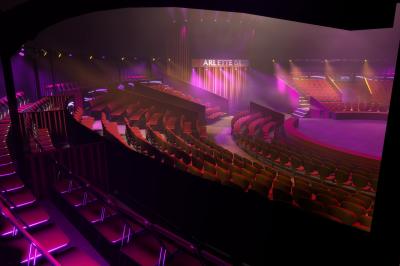 Miniature Location salle Thionville (Moselle) - Chapiteaux Arlette Gruss Thionville #8 Personnes dansant sous des éclairages colorés dans une salle sombre avec des gradins en arrière-plan.
