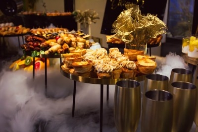 Buffet avec plats variés, incluant viandes grillées garnies de citron et légumes frais en présentation colorée.