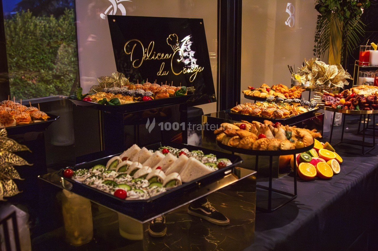 Buffet varié avec sandwiches, viennoiseries, fruits et plats décorés, présenté sur une table élégante.