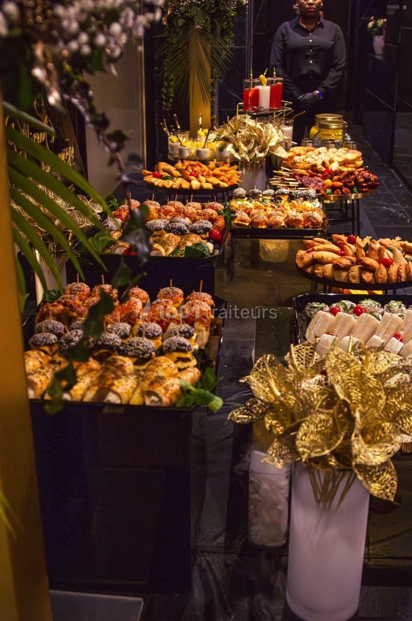 Buffet élégant avec une variété de pâtisseries, canapés et décorations dorées dans un cadre raffiné.