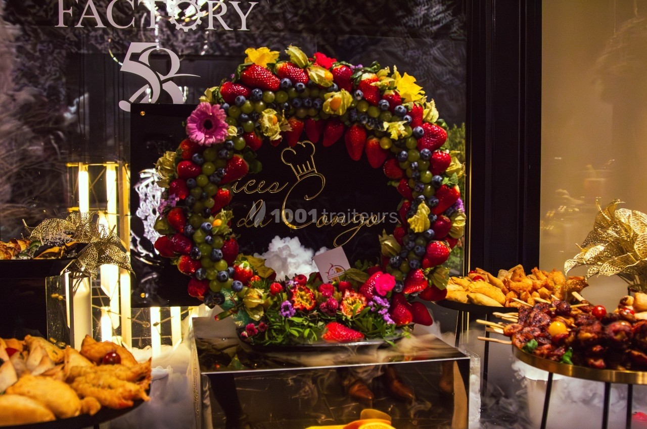 Couronne décorative composée de fruits colorés entourée de plats variés dans un cadre élégant.