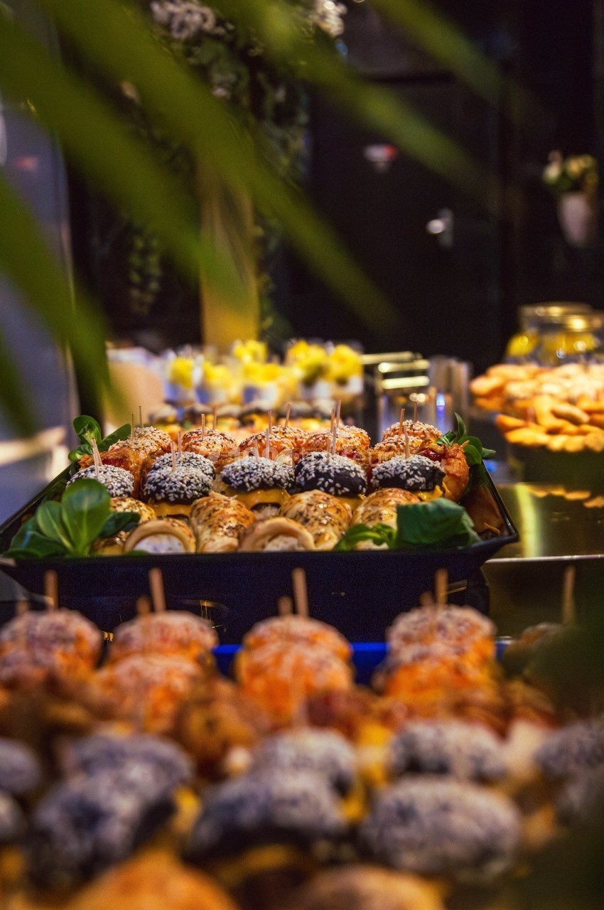 Plateau de bouchées variées avec des brochettes et des amuse-bouches, présenté sur une table dans un cadre festif.