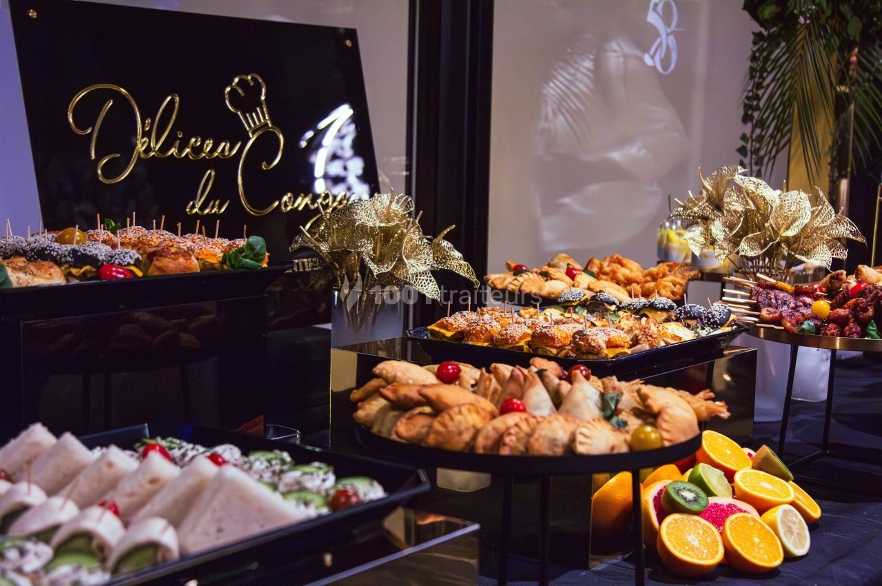 Buffet varié avec viennoiseries, fruits frais, sandwichs et décorations festives dorées.