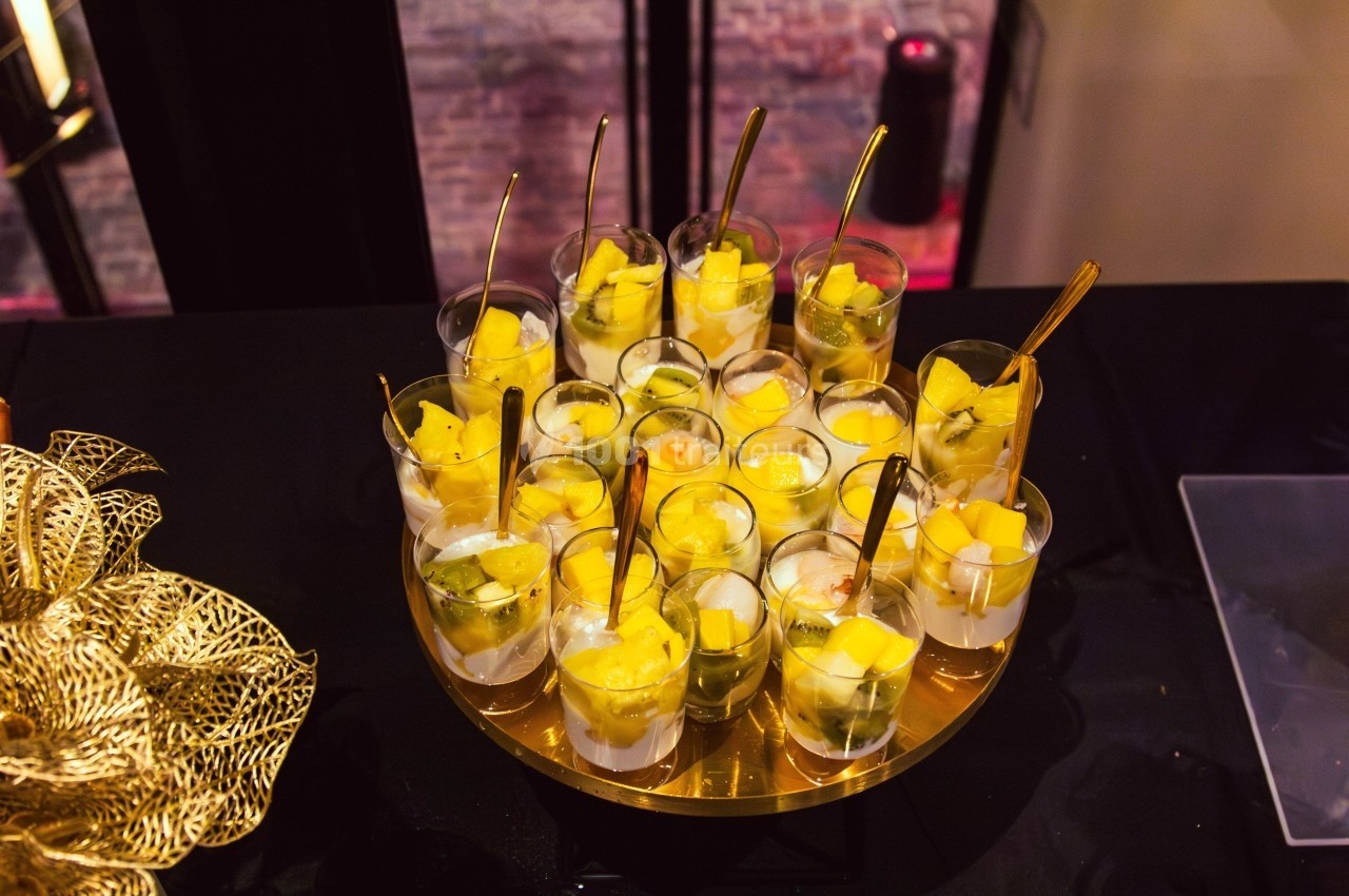 Verrines de fruits frais avec morceaux de mangue et kiwi, présentées sur un plateau doré.