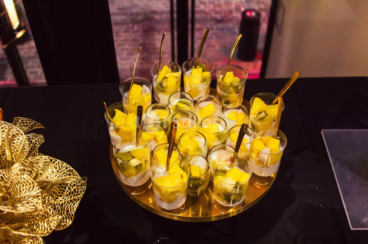 Verrines de fruits frais avec morceaux de mangue et kiwi, présentées sur un plateau doré.