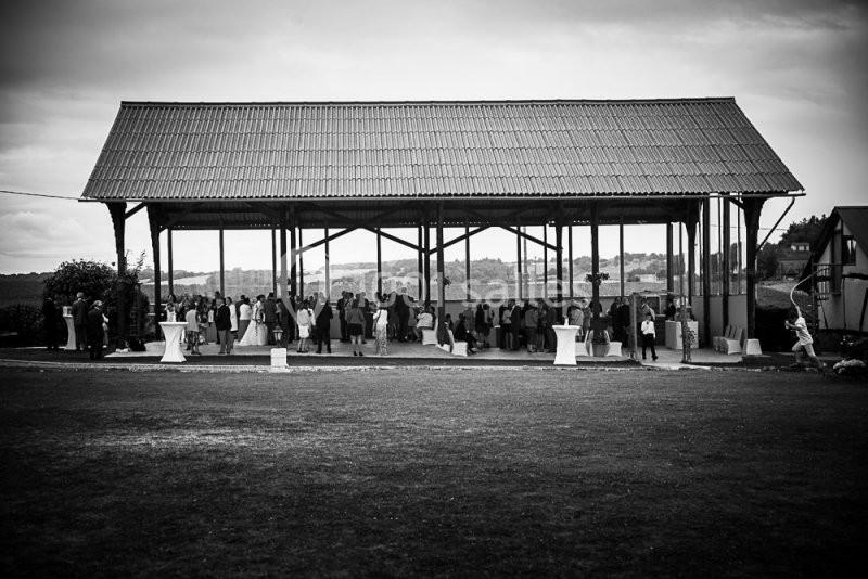 Un groupe de personnes rassemblées sous une grande structure ouverte en bois, dans un cadre rural.