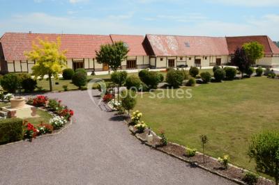 Salle de bain moderne avec douche vitrée, lavabo blanc, miroir, sèche-serviettes et poutres en bois apparentes.
