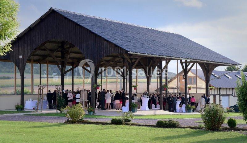 Un groupe de personnes rassemblées sous une grande structure en bois ouverte, entourée de verdure.