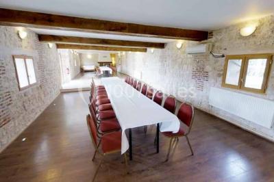 Salle de bain moderne avec douche vitrée, lavabo blanc, miroir, sèche-serviettes et poutres en bois apparentes.