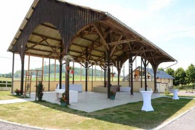 Salle de bain moderne avec douche vitrée, lavabo blanc, miroir, sèche-serviettes et poutres en bois apparentes.