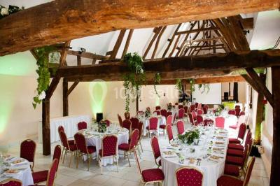 Salle de bain moderne avec douche vitrée, lavabo blanc, miroir, sèche-serviettes et poutres en bois apparentes.