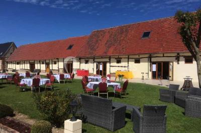 Salle de bain moderne avec douche vitrée, lavabo blanc, miroir, sèche-serviettes et poutres en bois apparentes.