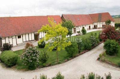 Salle de bain moderne avec douche vitrée, lavabo blanc, miroir, sèche-serviettes et poutres en bois apparentes.