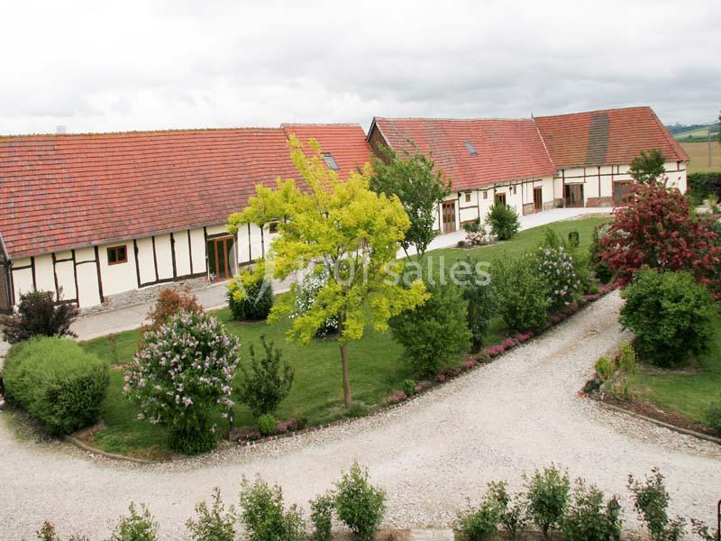Bâtiments à colombages avec toits en tuiles rouges entourés de jardins verdoyants et chemins gravillonnés.