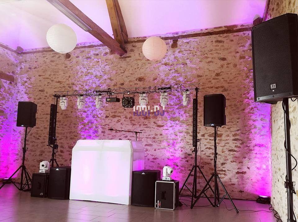 Installation de matériel de sonorisation et éclairage dans une salle en pierre avec des lumières roses et blanches.