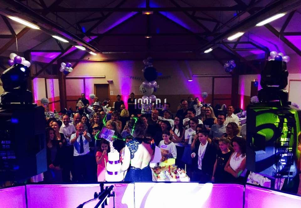 Un groupe de personnes rassemblées dans une salle décorée, éclairée par des lumières colorées, lors d'un événement festif.