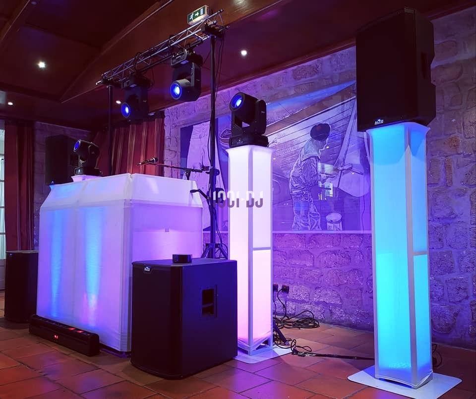 Installation de matériel de sonorisation et d'éclairage avec des colonnes lumineuses dans une salle en pierre.