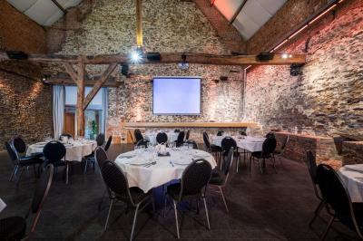 Salle lumineuse avec bar en bois, tables en verre, chaises noires et grandes fenêtres laissant entrer la lumière naturelle.