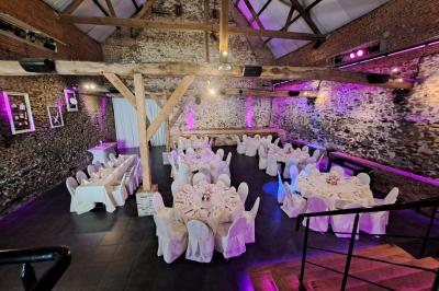 Salle lumineuse avec bar en bois, tables en verre, chaises noires et grandes fenêtres laissant entrer la lumière naturelle.