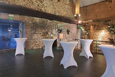 Salle lumineuse avec bar en bois, tables en verre, chaises noires et grandes fenêtres laissant entrer la lumière naturelle.
