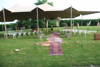Salle lumineuse avec bar en bois, tables en verre, chaises noires et grandes fenêtres laissant entrer la lumière naturelle.