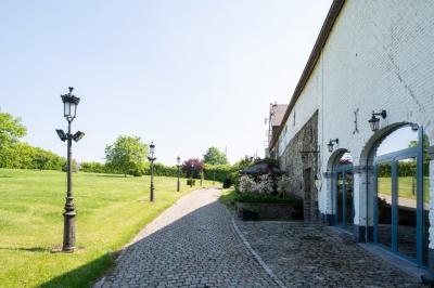 Miniature Location salle Tubize (Brabant wallon) - Praesenti #4 Salle en briques avec poutres apparentes, tables hautes noires et grandes ouvertures donnant sur un espace extérieur.