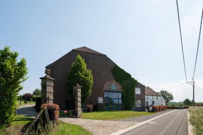 Miniature Location salle Tubize (Brabant wallon) - Praesenti #5 Salle en briques avec poutres apparentes, tables hautes noires et grandes ouvertures donnant sur un espace extérieur.