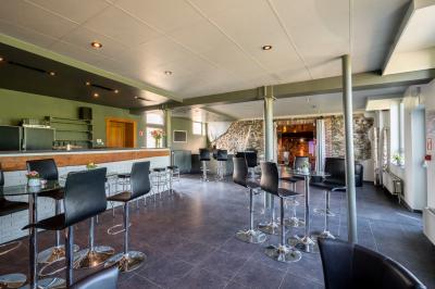 Miniature Location salle Tubize (Brabant wallon) - Praesenti #7 Salle en briques avec poutres apparentes, tables hautes noires et grandes ouvertures donnant sur un espace extérieur.