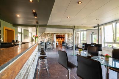 Miniature Location salle Tubize (Brabant wallon) - Praesenti #8 Salle en briques avec poutres apparentes, tables hautes noires et grandes ouvertures donnant sur un espace extérieur.