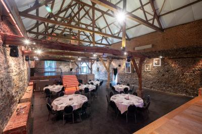 Miniature Location salle Tubize (Brabant wallon) - Praesenti #11 Salle en briques avec poutres apparentes, tables hautes noires et grandes ouvertures donnant sur un espace extérieur.