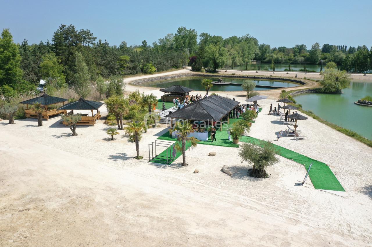 Vue aérienne d'un espace extérieur avec terrasses ombragées, palmiers, bassins d'eau et allées aménagées.
