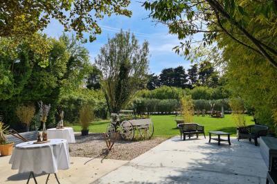 Salle vide avec un sol en parquet sombre, murs blancs, fenêtres et piliers gris sous un plafond à dalles blanches.