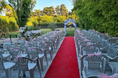 Salle vide avec un sol en parquet sombre, murs blancs, fenêtres et piliers gris sous un plafond à dalles blanches.