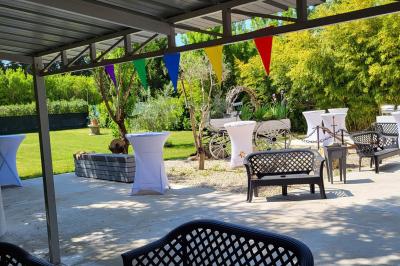 Salle vide avec un sol en parquet sombre, murs blancs, fenêtres et piliers gris sous un plafond à dalles blanches.
