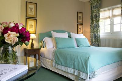 Deux chaises en bois et une table ronde avec un seau à glace sur une terrasse donnant sur un jardin verdoyant.