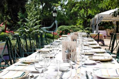 Deux chaises en bois et une table ronde avec un seau à glace sur une terrasse donnant sur un jardin verdoyant.