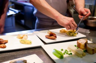 Deux chaises en bois et une table ronde avec un seau à glace sur une terrasse donnant sur un jardin verdoyant.