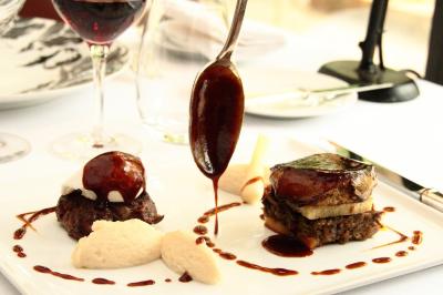 Deux chaises en bois et une table ronde avec un seau à glace sur une terrasse donnant sur un jardin verdoyant.