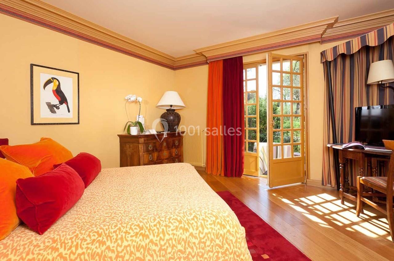 Chambre lumineuse avec lit double, décor chaleureux, meubles en bois, et porte-fenêtre ouverte sur un jardin.