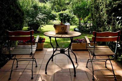 Deux chaises en bois et une table ronde avec un seau à glace sur une terrasse donnant sur un jardin verdoyant.