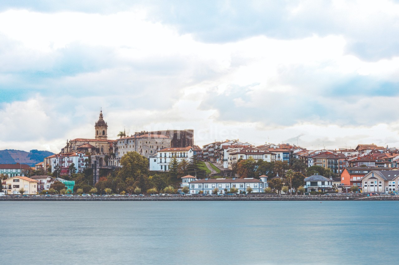 Vue d'une ville côtière avec des bâtiments historiques, une église et des maisons colorées au bord de l'eau.