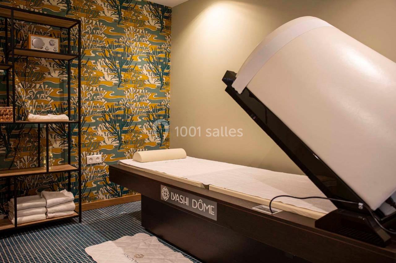 Salle de bien-être avec un lit équipé d'un dôme de soin, entourée d'une décoration murale colorée et d'étagères.