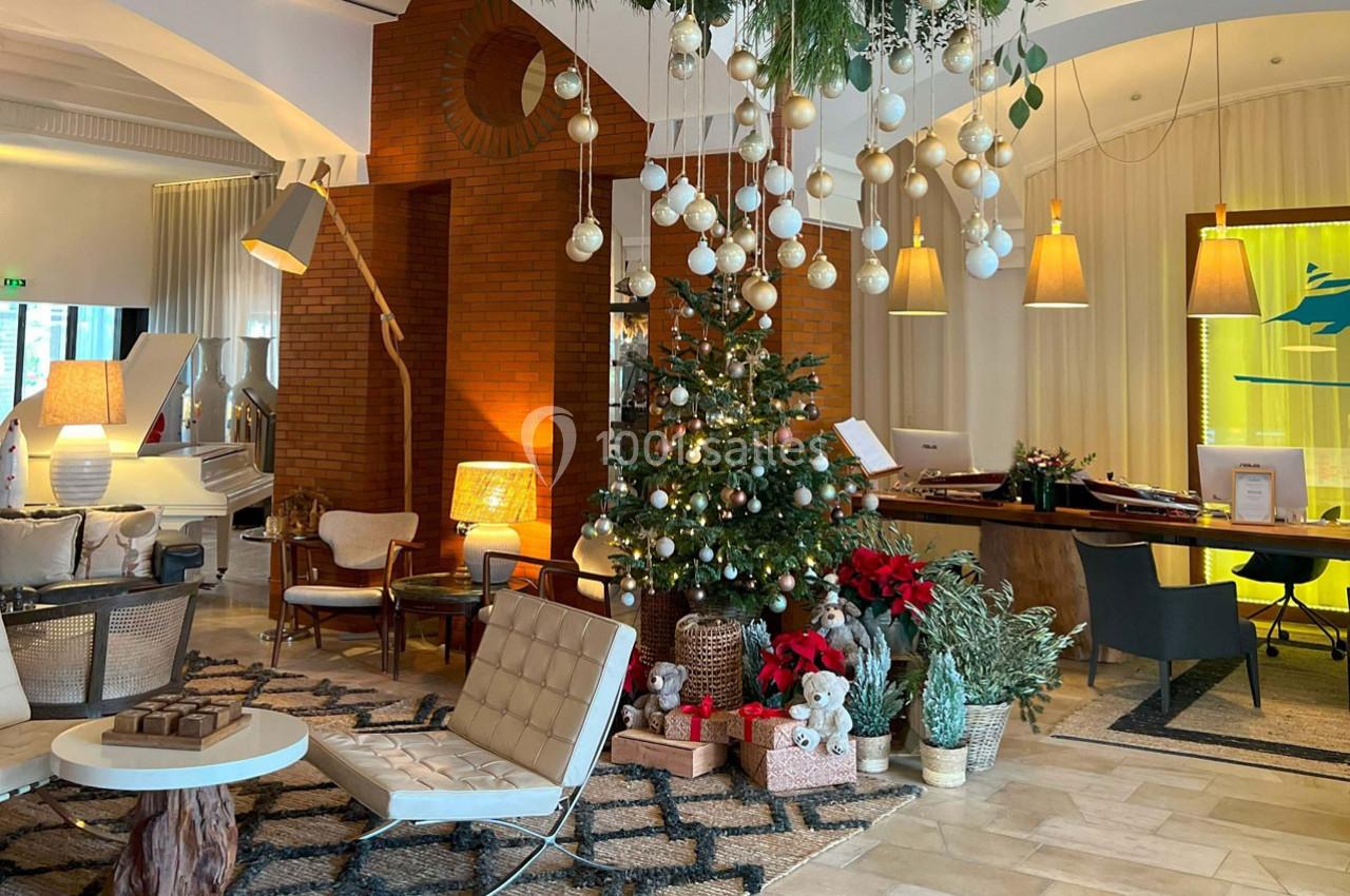 Décoration festive dans un salon élégant avec un sapin de Noël, des guirlandes suspendues et des meubles modernes.
