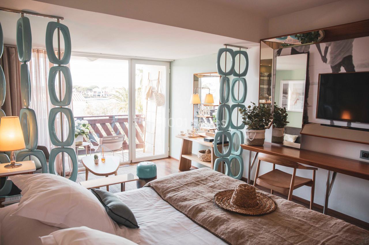 Chambre lumineuse avec lit double, bureau, télévision, balcon aménagé et décoration moderne en tons naturels.