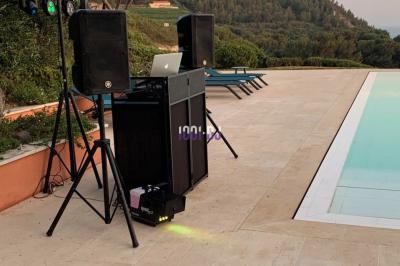 Personnes dans une ambiance tamisée, discutant et dansant près d'un bar décoré de fleurs suspendues.