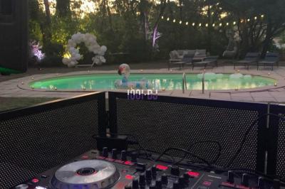 Personnes dans une ambiance tamisée, discutant et dansant près d'un bar décoré de fleurs suspendues.