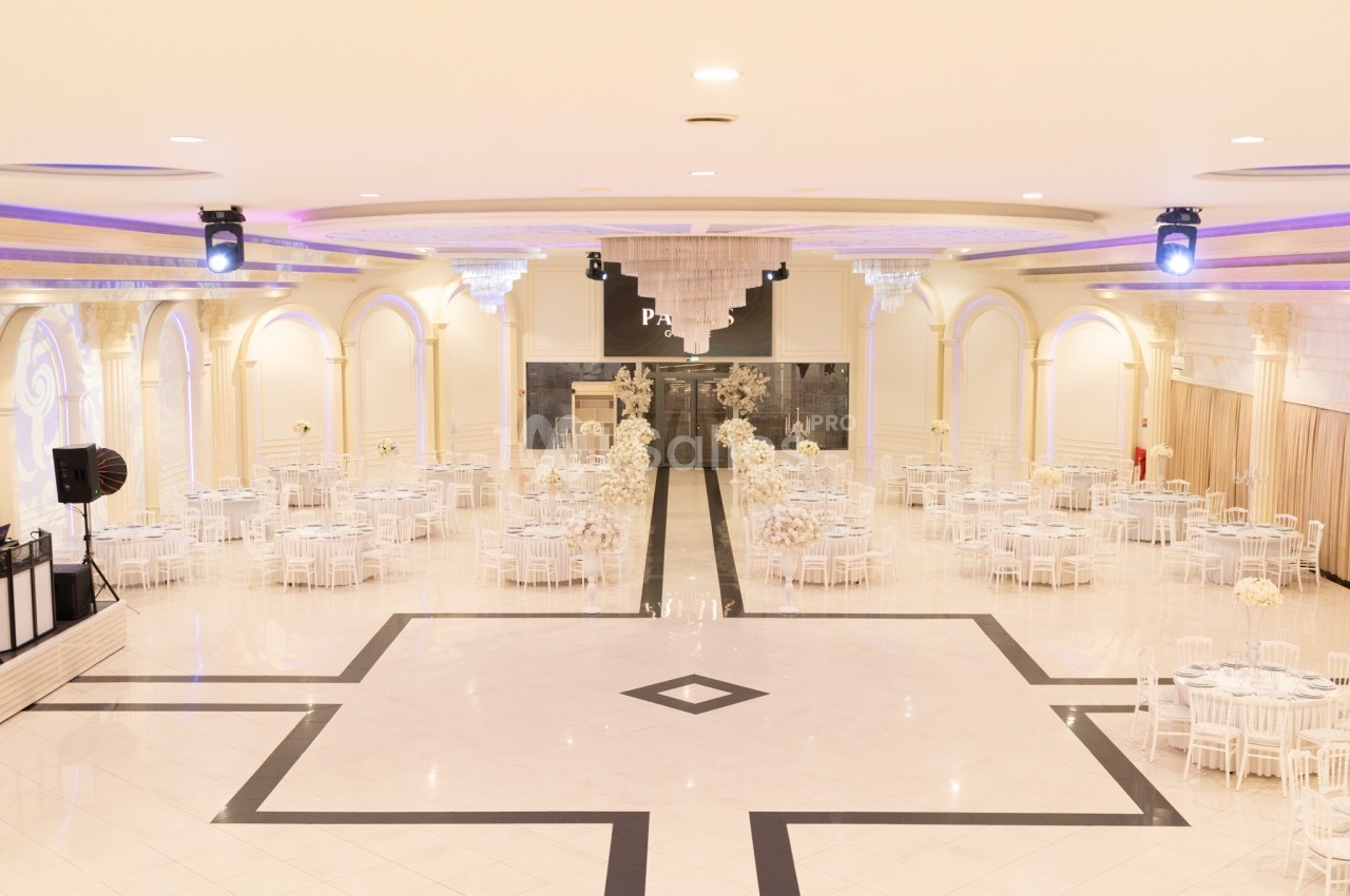 Salle de réception spacieuse avec tables rondes décorées de fleurs blanches et éclairage élégant.